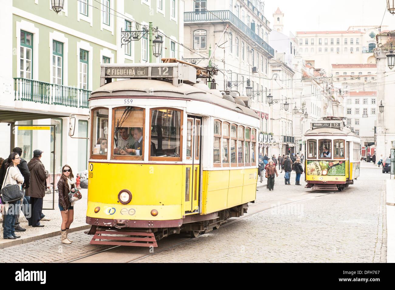 Les trams jaunes historique dans une rue pavée en place Figueira (AKA Praça da Figueira) dans la vieille ville de Lisbonne, Portugal Banque D'Images