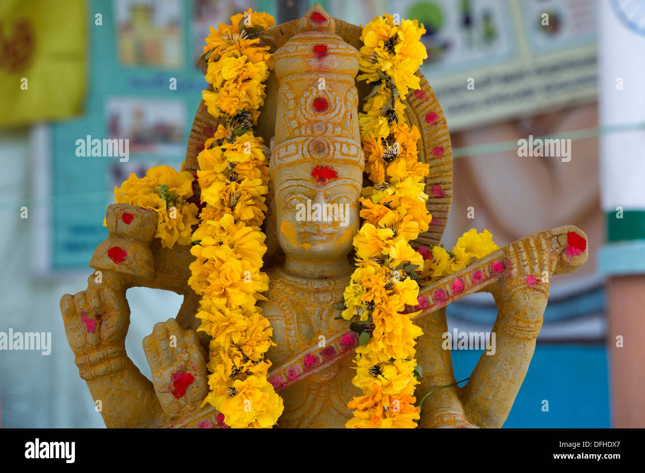 Déesse hindoue en pierre statue de Saraswati et de fleurs. L'Andhra Pradesh, Inde Banque D'Images