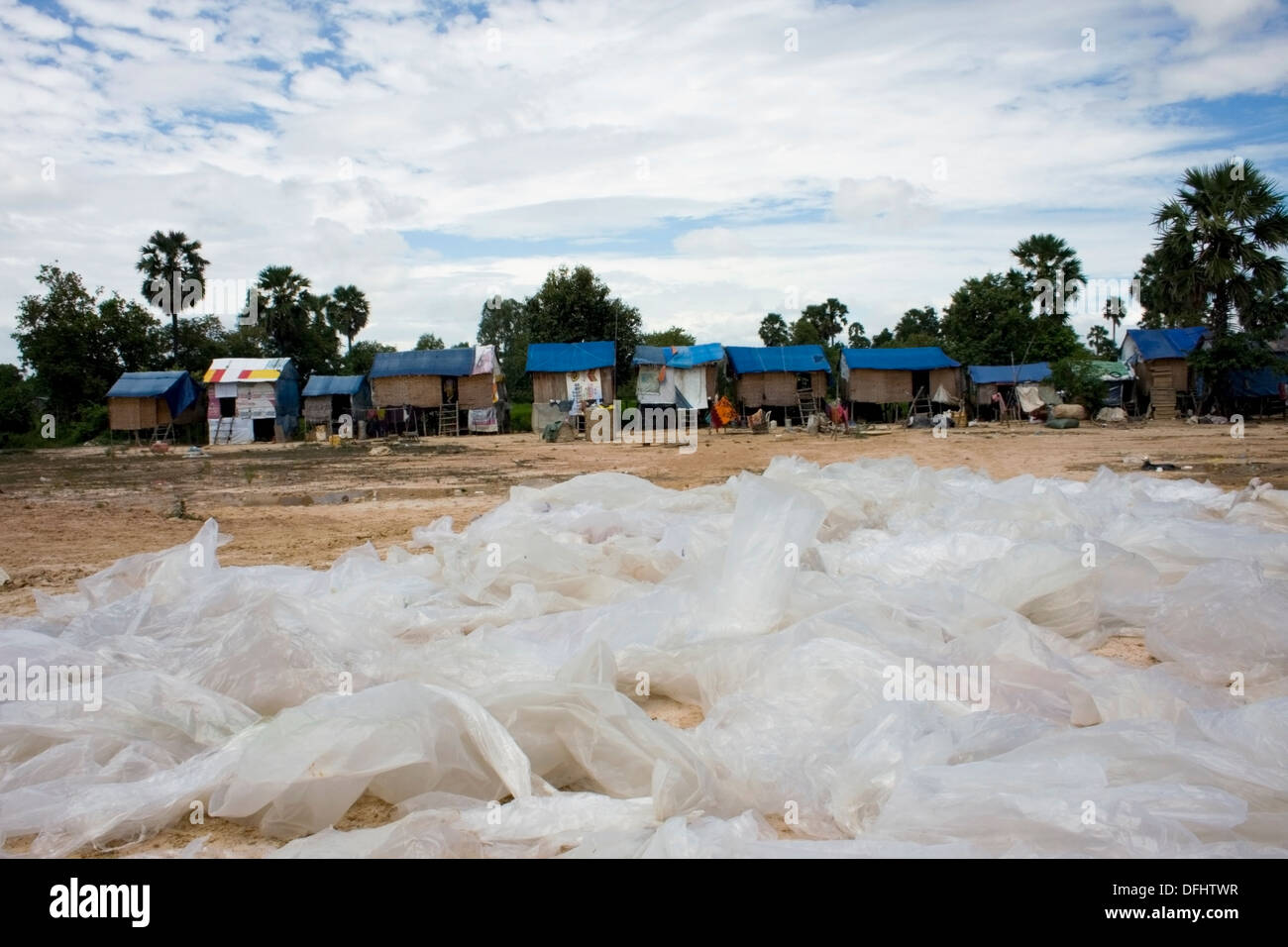 De grands sacs en plastique sont empilés près des maisons des personnes qui travaillent à un dépôt de recyclage des ordures à Phnom Penh, Cambodge. Banque D'Images