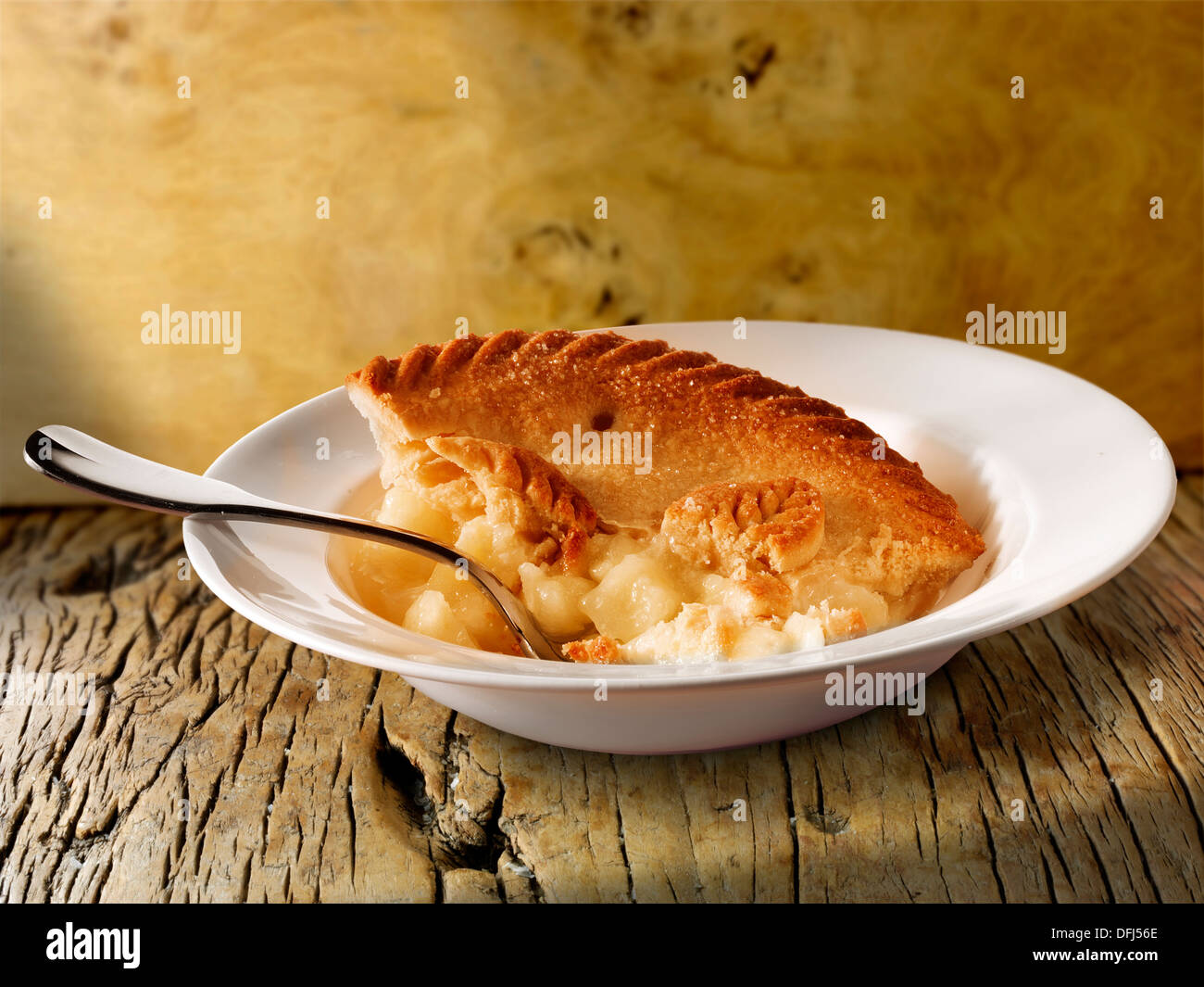 La traditionnelle tarte aux pommes et crème anglaise au lait servi dans un bol sur une table en bois Banque D'Images