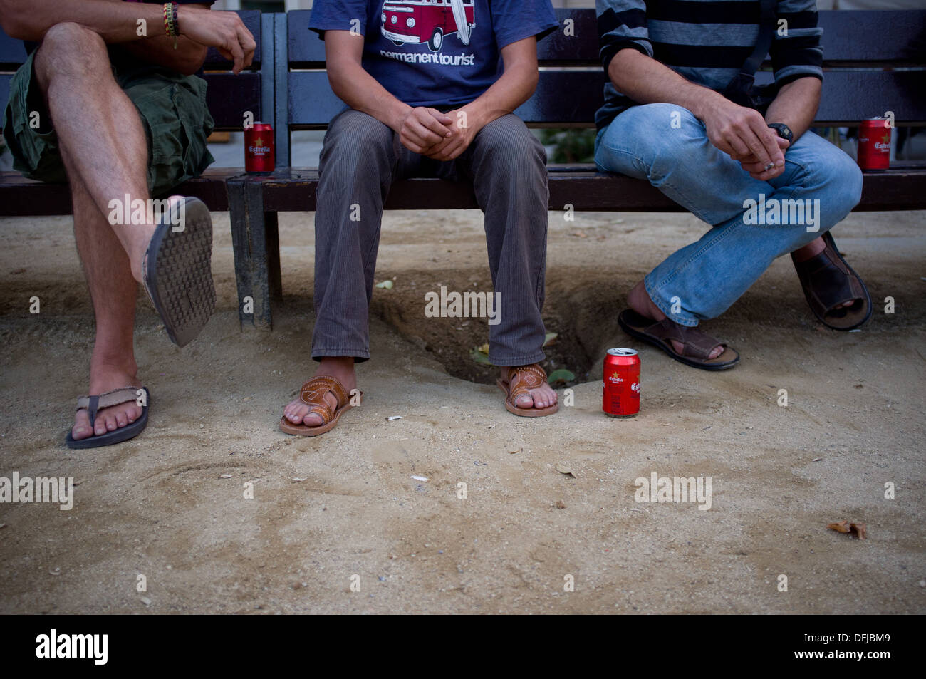 Trois jeunes hommes assis sur un banc et boire de la bière à Barcelone, Espagne. Banque D'Images