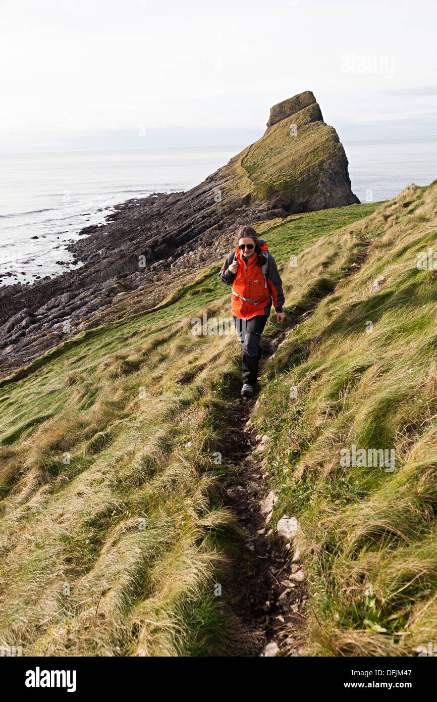 Femme marche sur la partie extérieure du Worm's Head montrant érodé sentier, Rhossili, Gower, Pays de Galles, Royaume-Uni Banque D'Images