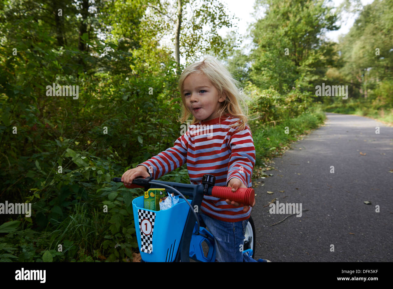 L'équilibre de l'enfant blond girl riding Bike in forest road, l'été Banque D'Images