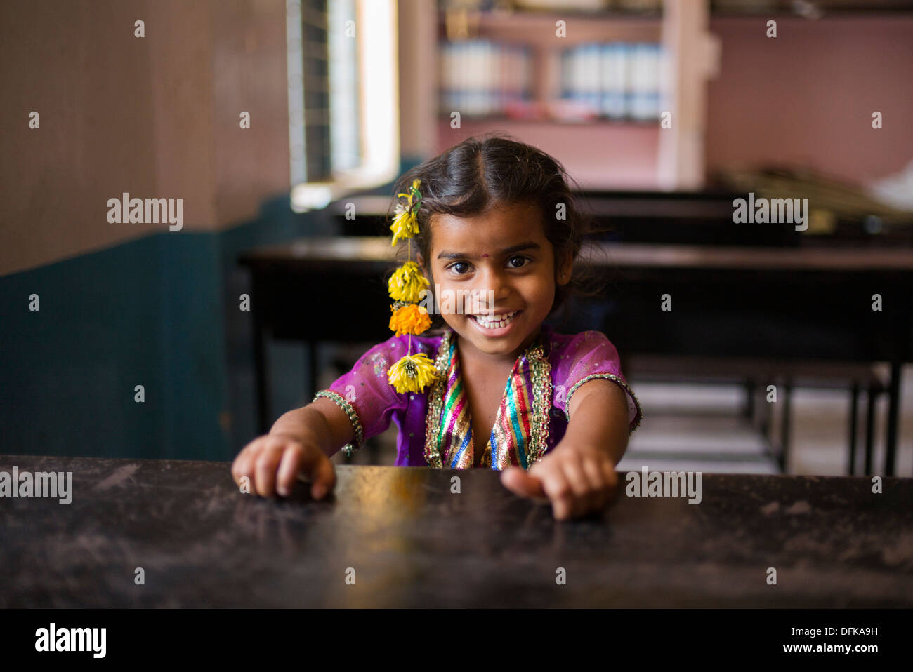 Jeune indienne assis à un bureau de l'école en souriant. L'Andhra Pradesh, Inde Banque D'Images