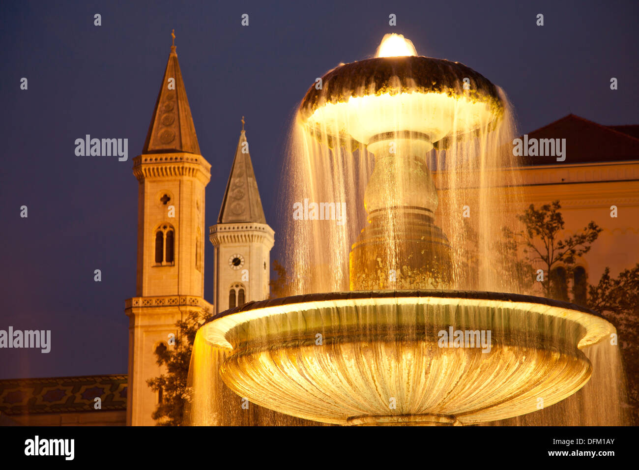 Fontaine illuminée en face de l'université et l'église Saint Louis à Munich, Bavière, Allemagne Banque D'Images