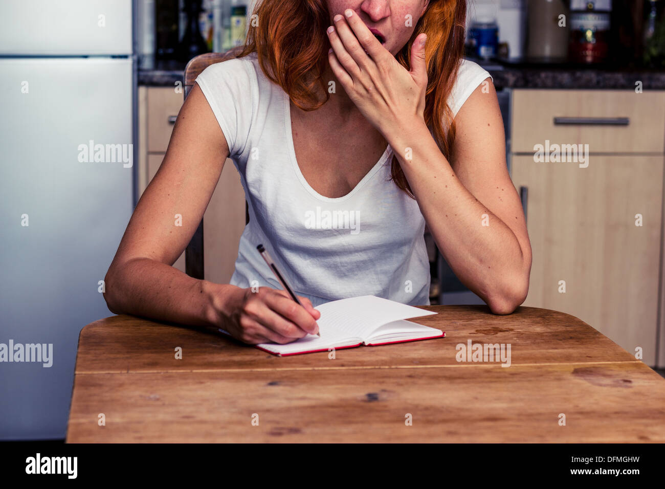 Assez jeune femme prenait des notes dans sa cuisine Banque D'Images