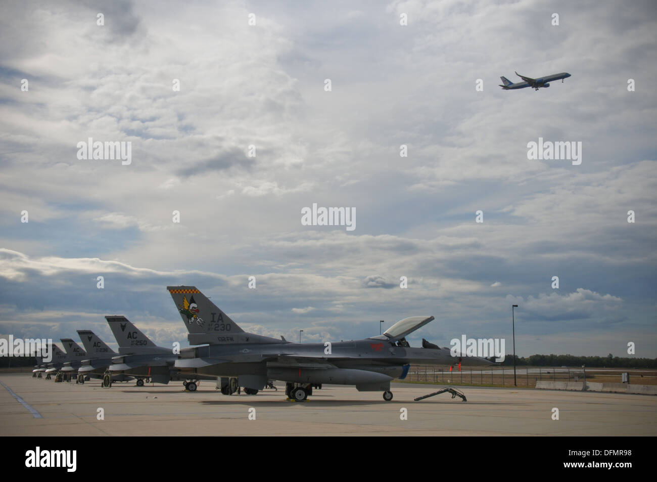 Une rangée de U.S. Air Force F-16C Fighting Falcon s'asseoir sur la ligne de vol sur Septembre 26 à la 177e Escadre de chasse à l'Atlantic City Air National Guard Base, N.J. comme un C-32 de l'US Air Force à partir de la 89e Escadre de transport aérien à Joint Base Andrews, Md., vole au-dessus. Banque D'Images