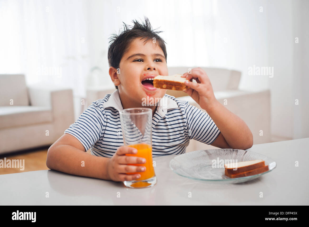 Boy eating toast avec du jus d'orange Banque D'Images