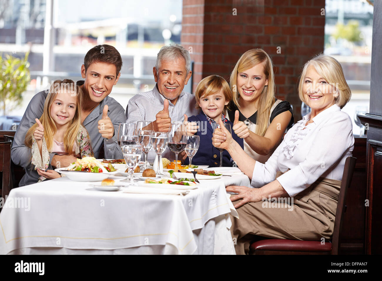 Famille heureuse de féliciter restaurant tenant leurs Thumbs up Banque D'Images