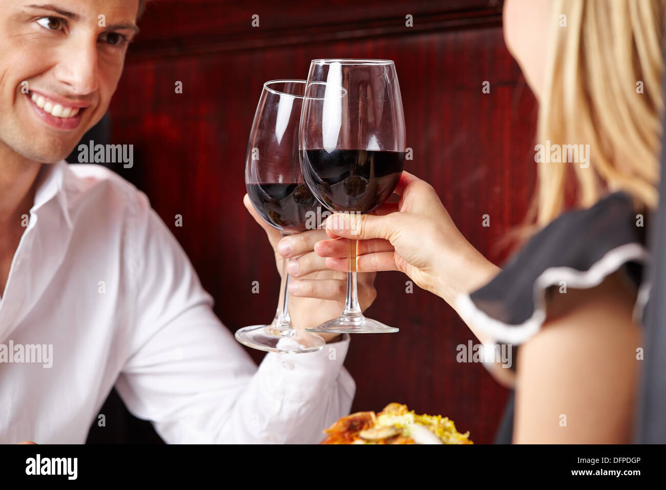 Heureux couple clinking glasses of red wine in a restaurant Banque D'Images