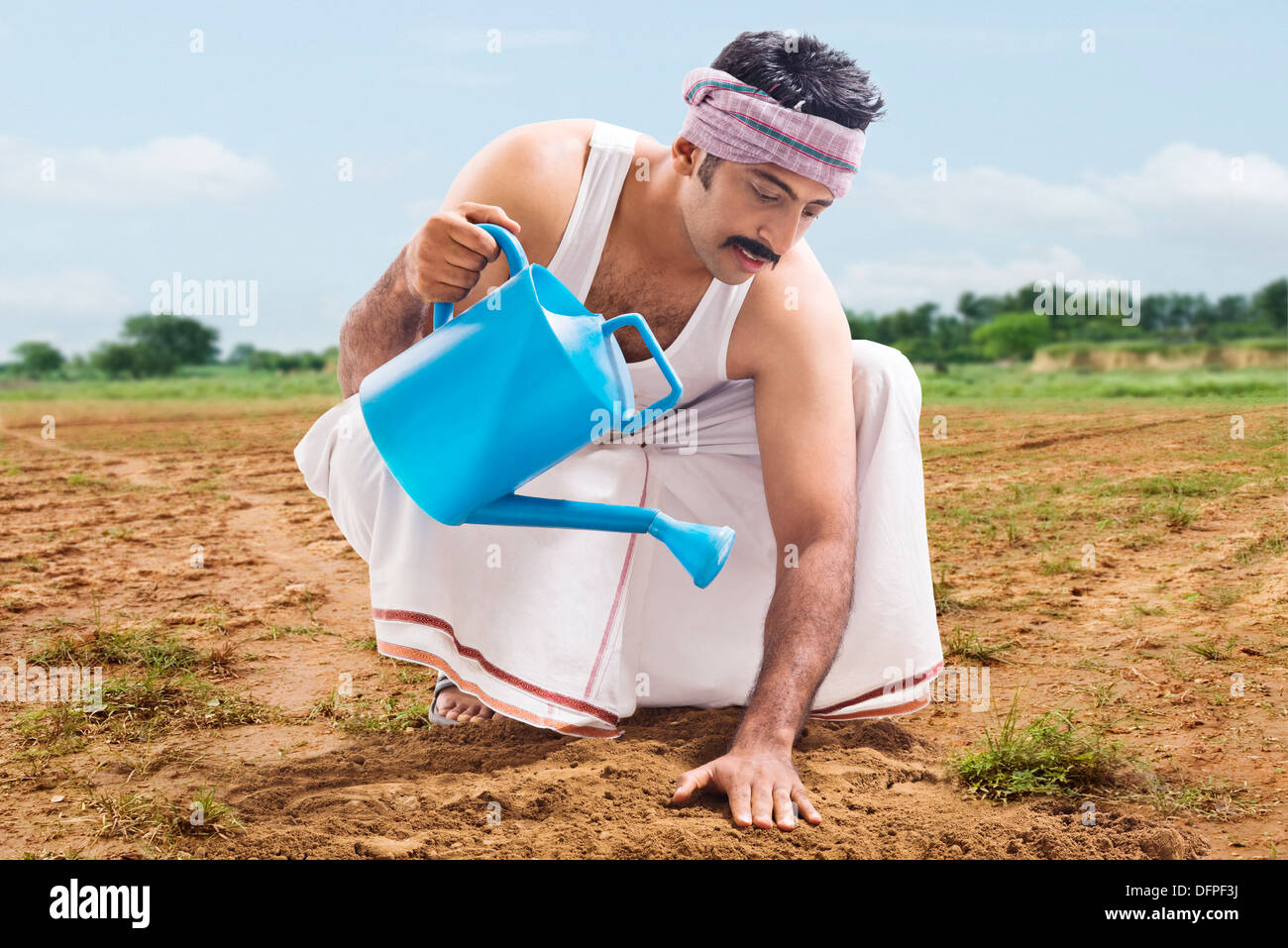 Farmer watering sol dans un champ Banque D'Images