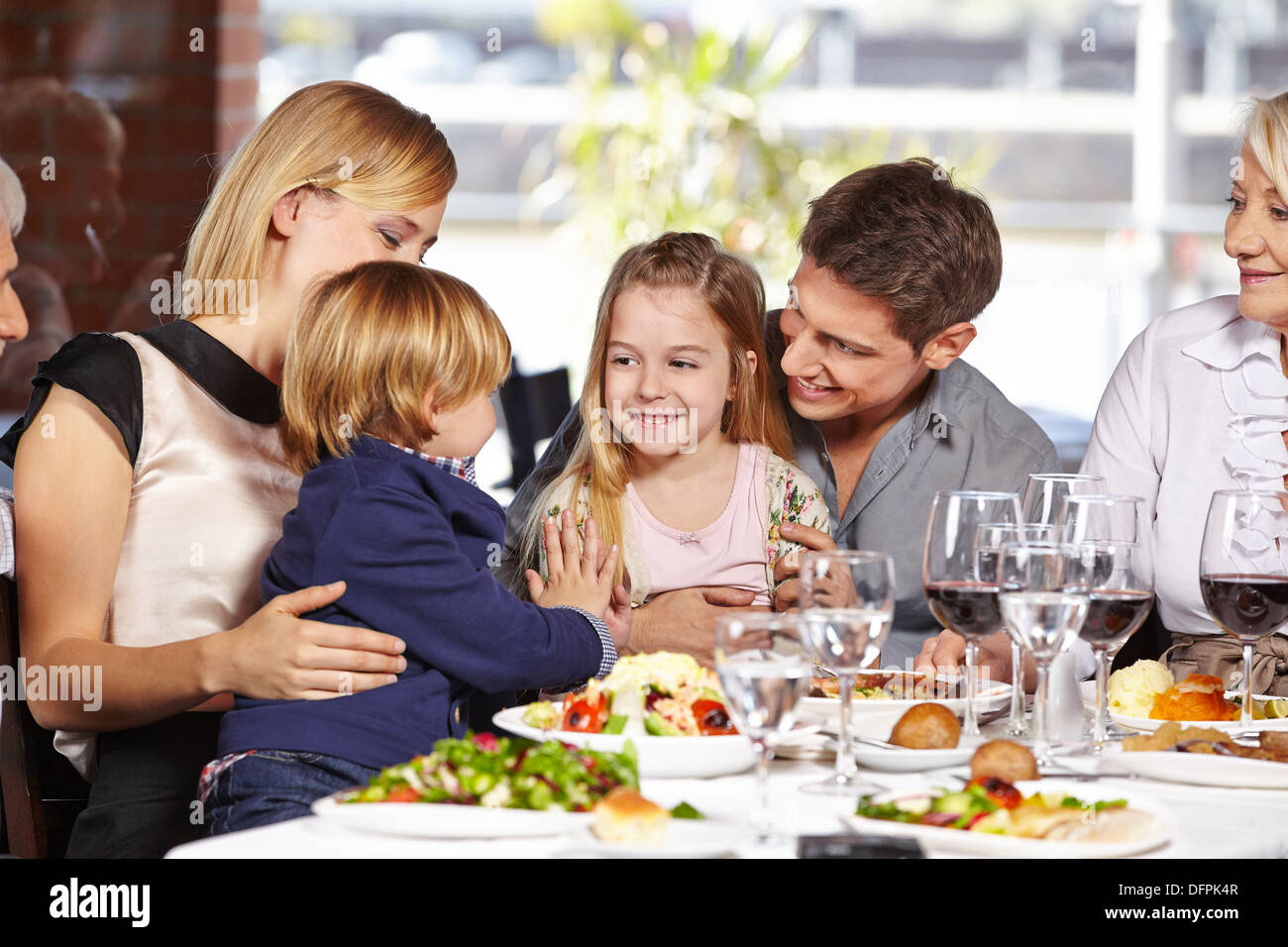 Deux enfants jouant ensemble dans un restaurant au cours d'une visite familiale Banque D'Images