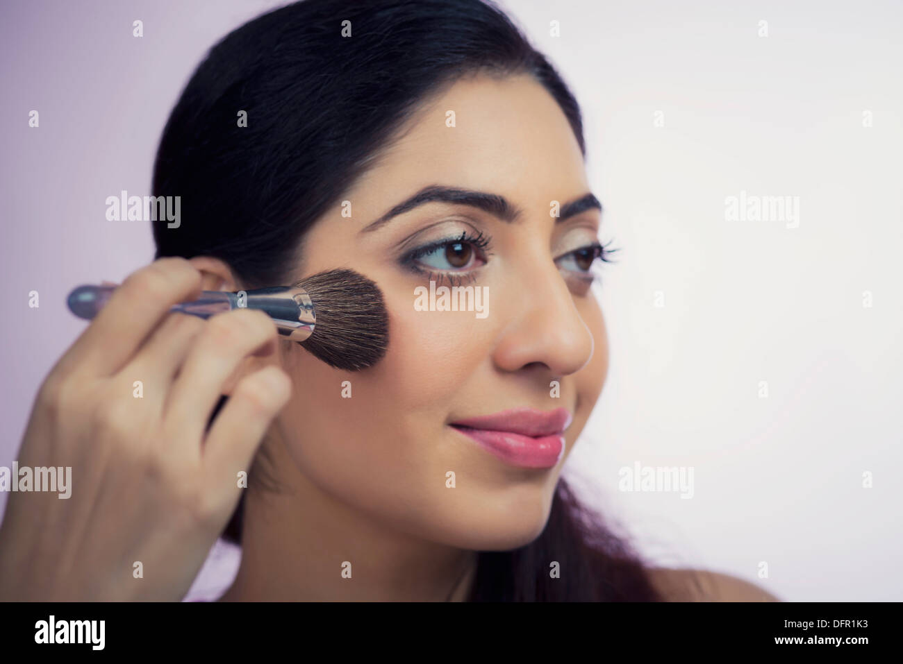 Close-up of a woman applying make-up sur son visage avec un pinceau de maquillage Banque D'Images