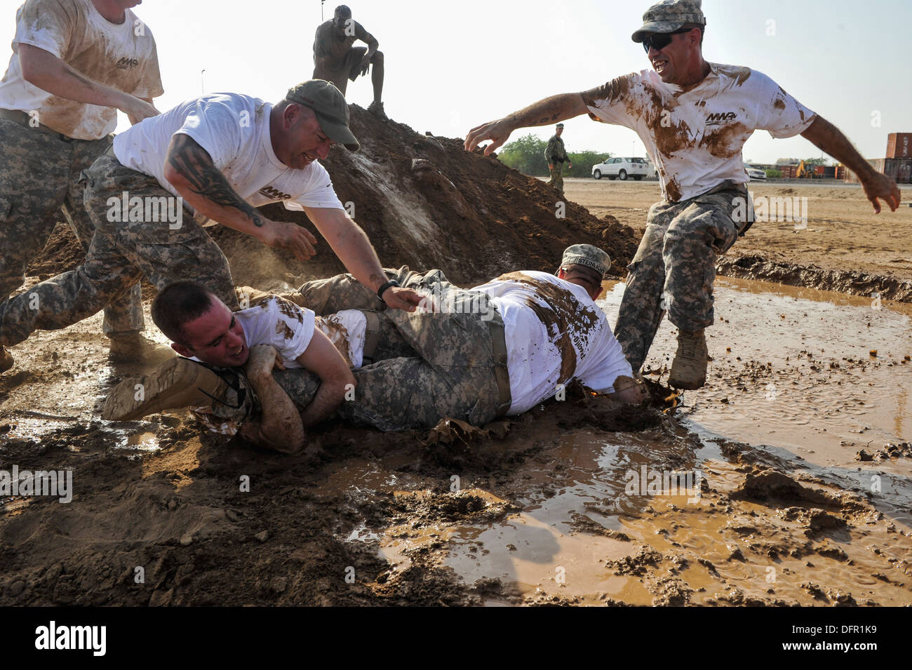 Le personnel de la course aux prises les uns les autres dans une fosse de boue pendant la Mud Run 5K au Camp Lemonnier. Banque D'Images