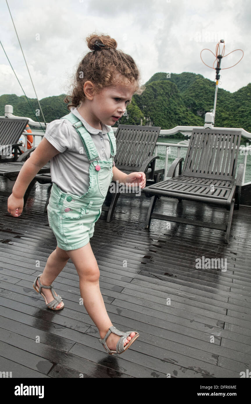 Propriétaire du navire : fille mignonne avec des cheveux bouclés à bord d'un bateau de croisière dans la baie d'Halong, Vietnam Banque D'Images