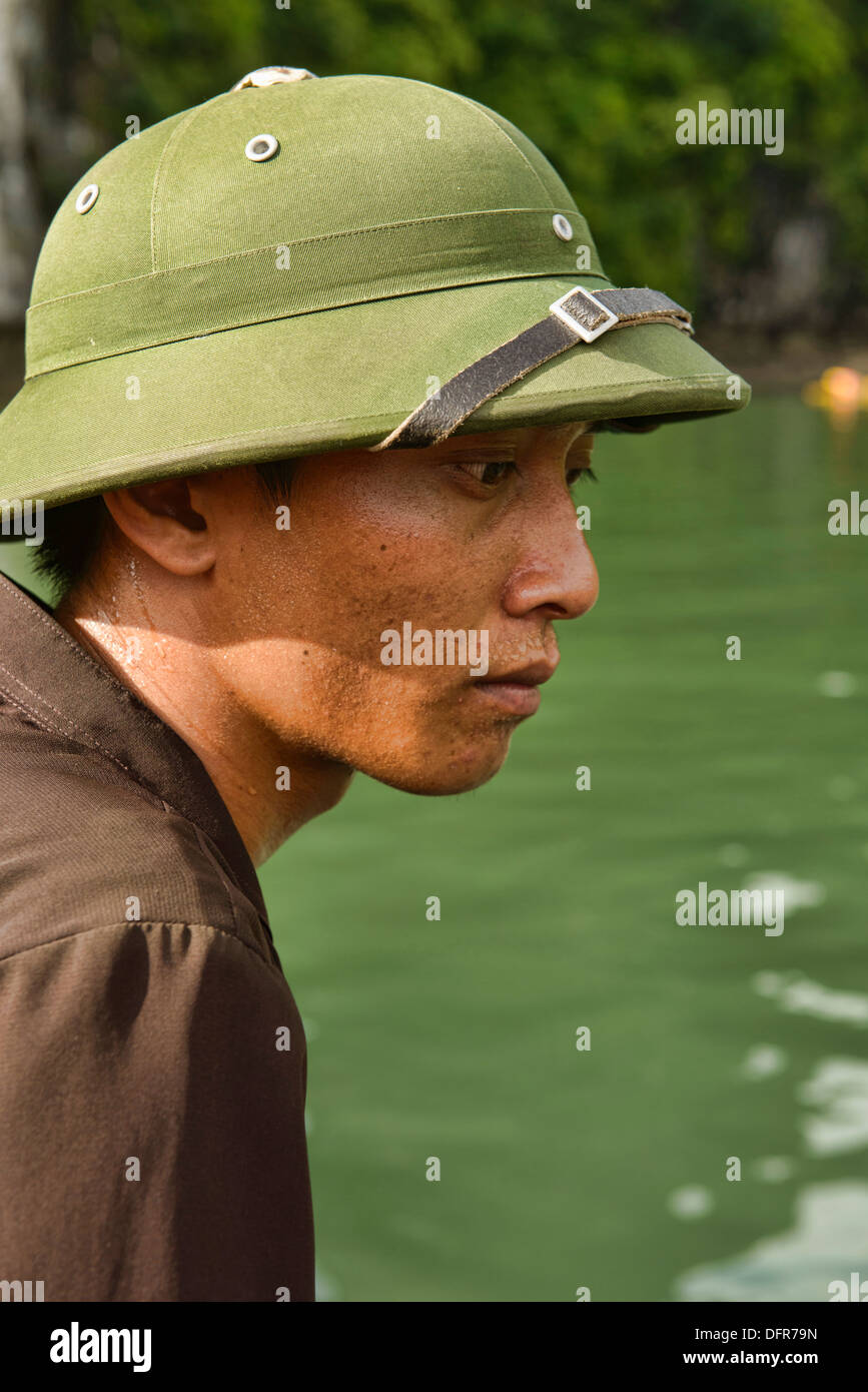 Portrait d'un conducteur de bateau dans un casque colonial dans la baie d'Halong, Vietnam Banque D'Images