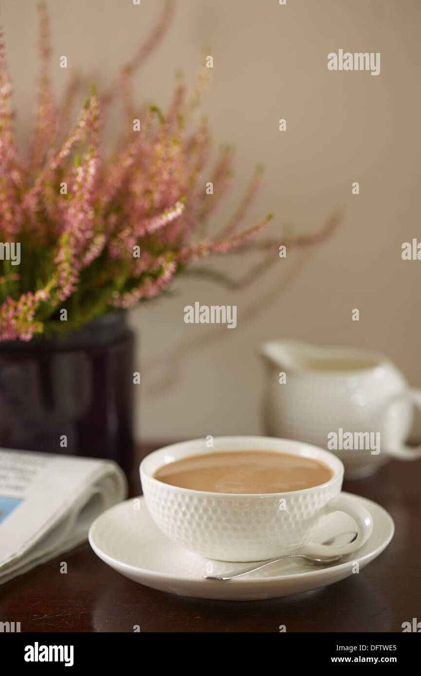 Café au lait sur une table le dimanche matin avec un journal et des plantes Banque D'Images