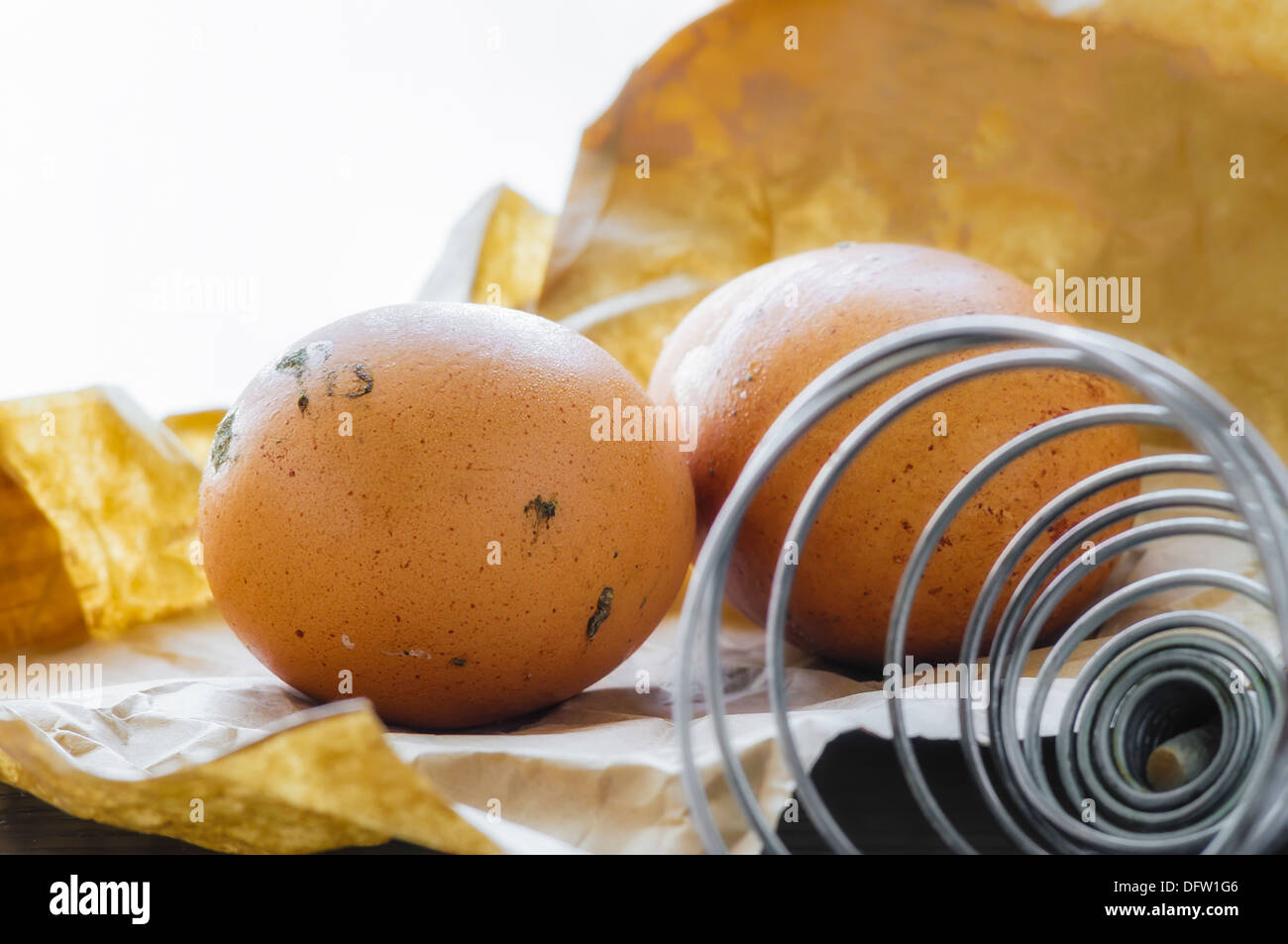 Deux œufs frais juste posées, sur un sac en papier brun avec un fouet spirale Banque D'Images