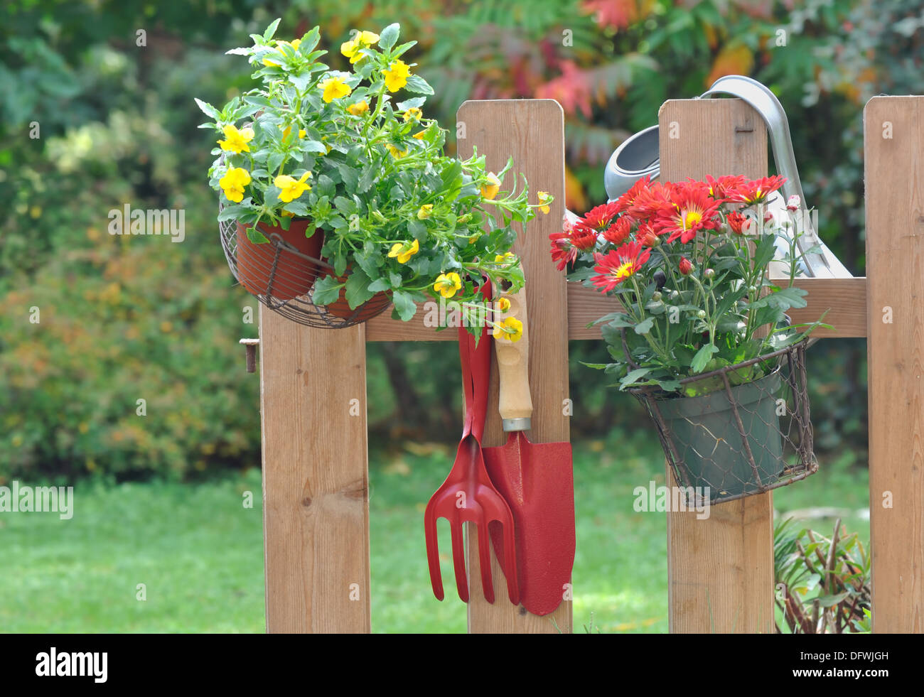 Outils de jardinage et pot de fleur suspendu à une clôture Banque D'Images