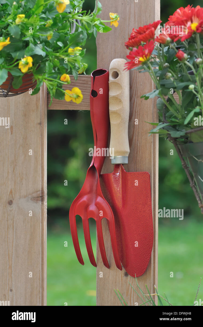 Outils de jardinage et pot de fleur suspendu à une clôture Banque D'Images