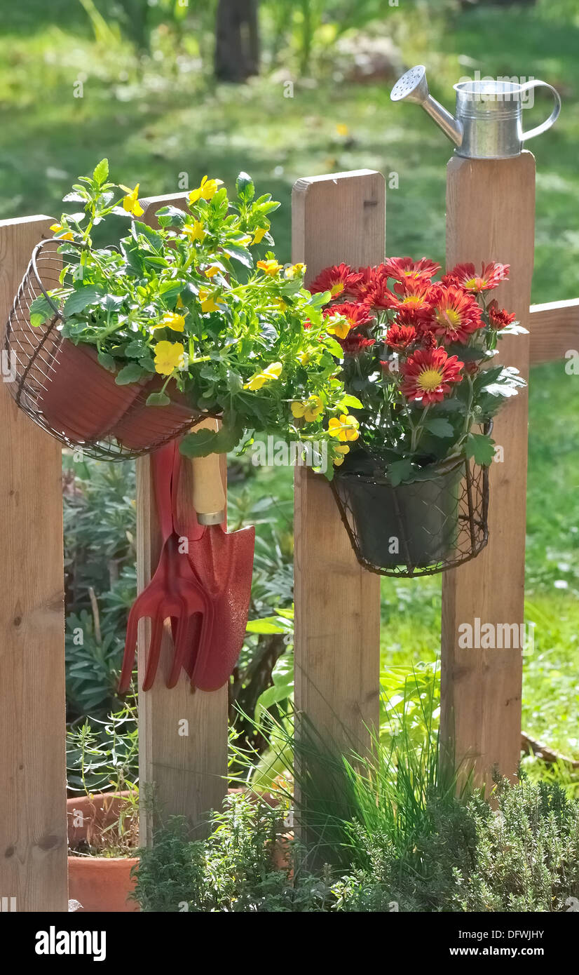 Outils de jardinage et pot de fleur suspendu à une clôture Banque D'Images