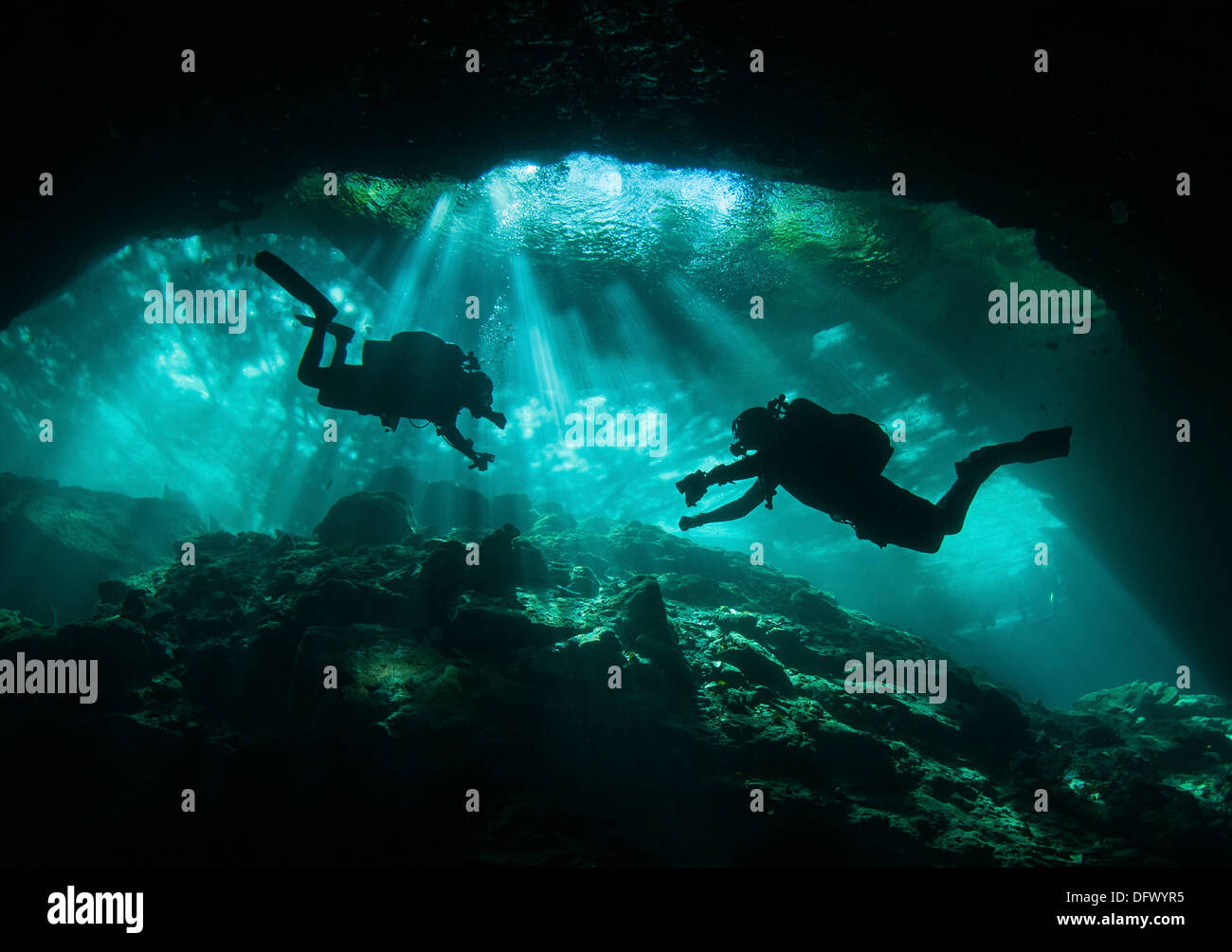 Deux plongeurs qui se profile à la lumière à l'entrée de Chac Mool cénote, le Mexique. Banque D'Images