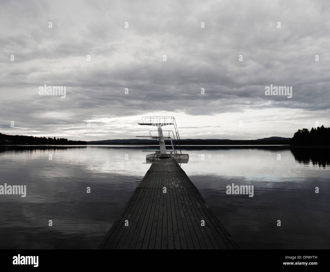 Les plates-formes de plongée à la fin du long quai sur le lac paisible au coucher du soleil Banque D'Images