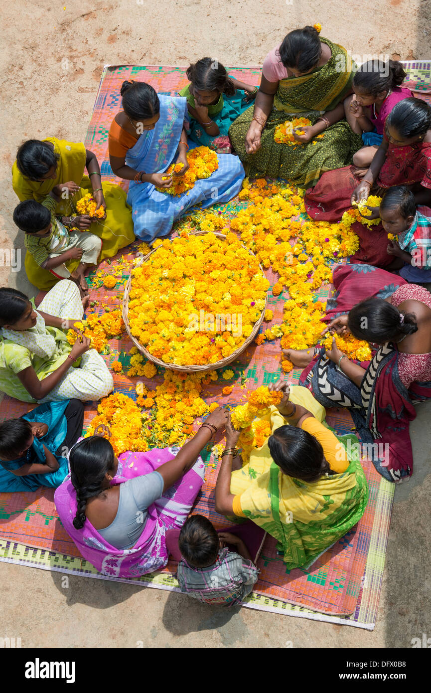 Village de l'Inde rurale de femmes et d'enfants assis autour d'un panier de fleurs de souci de faire des guirlandes de fleurs. L'Andhra Pradesh, Inde Banque D'Images