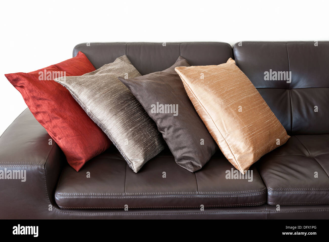 Quatre coussins colorés sur le canapé en cuir marron foncé Photo Stock -  Alamy