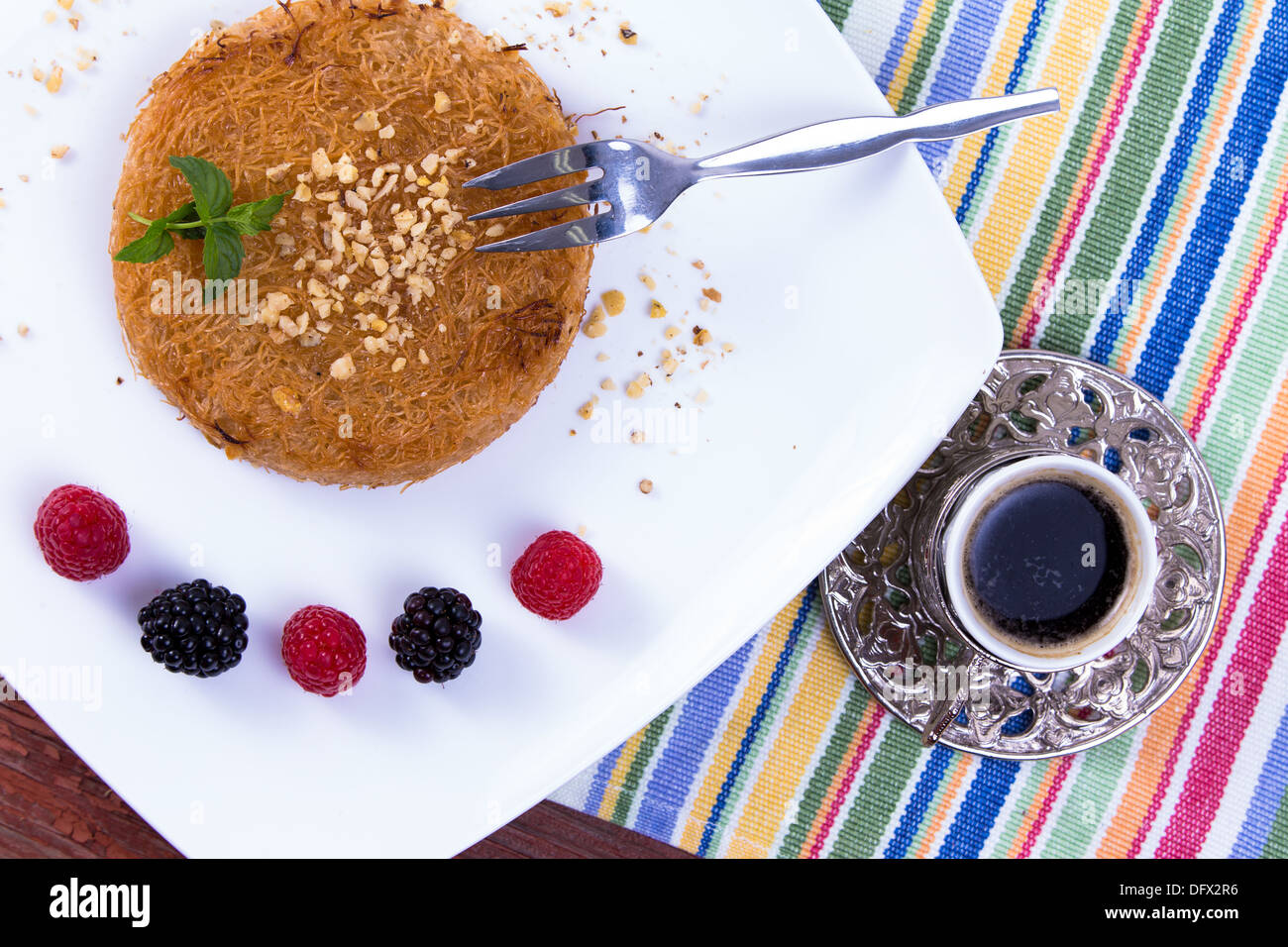 Kunefe dessert turc servi avec le café turc sur une plaque blanche avec les feuilles de menthe le long de baies rouges et noires sur un pique-nique tabl Banque D'Images