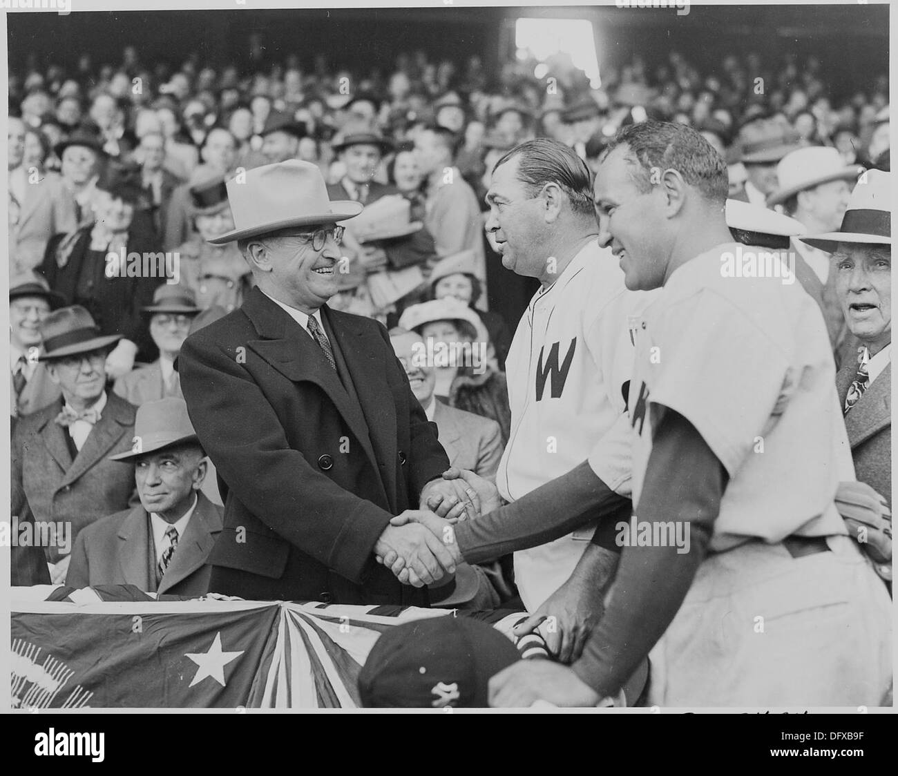 Une photographie historique capture le président Harry S. Truman serrant la main de l'entraîneur des sénateurs de Washington, Ossie Bluege, et de l'entraîneur des Yankees de New York, Bucky Harris, soulignant un moment de l'histoire du baseball américain. Banque D'Images