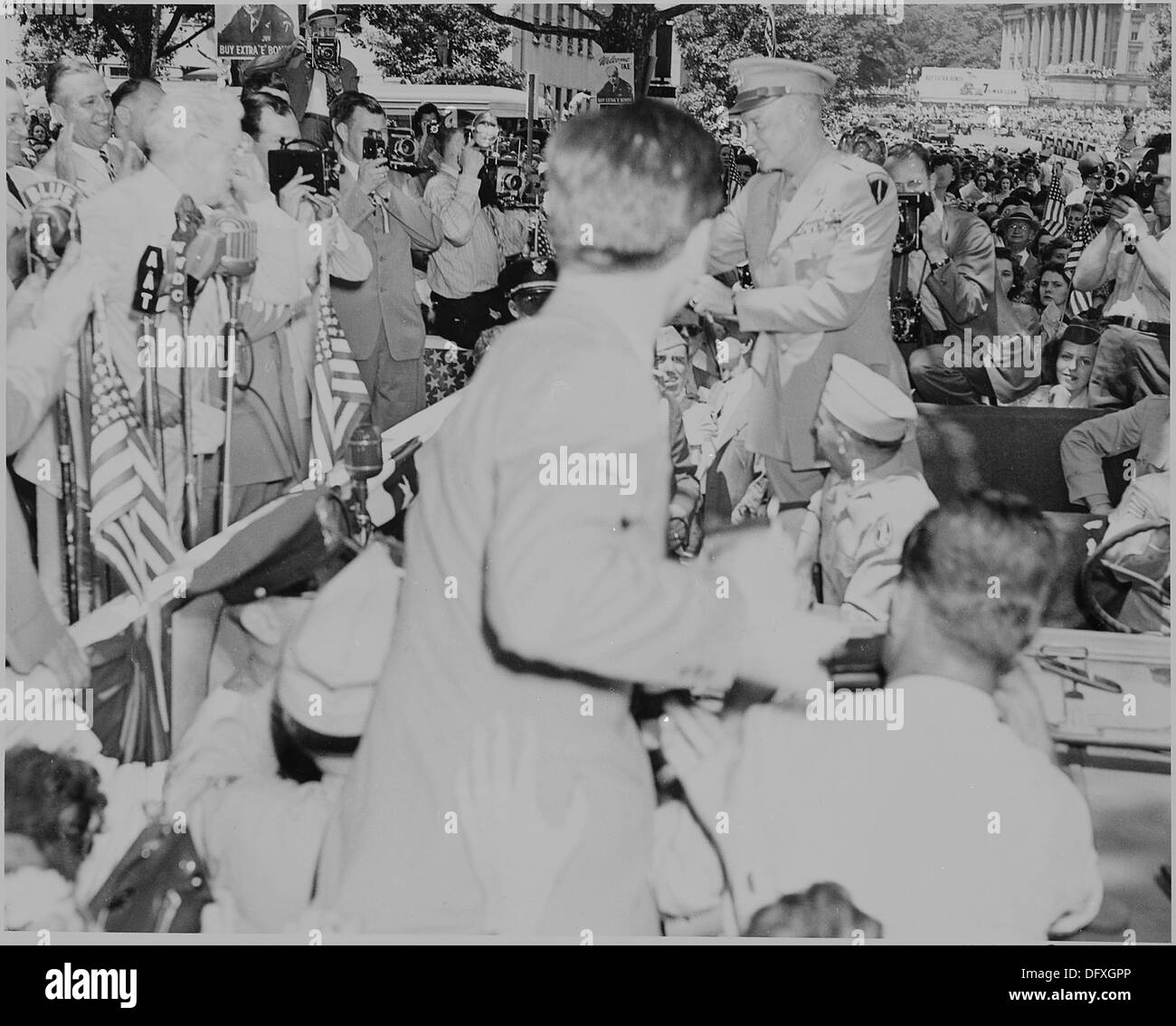 Une photographie du général Dwight D. Eisenhower debout à l'arrière de sa jeep, entouré de photographes et de foules acclamées, célébrant probablement un moment important. Banque D'Images