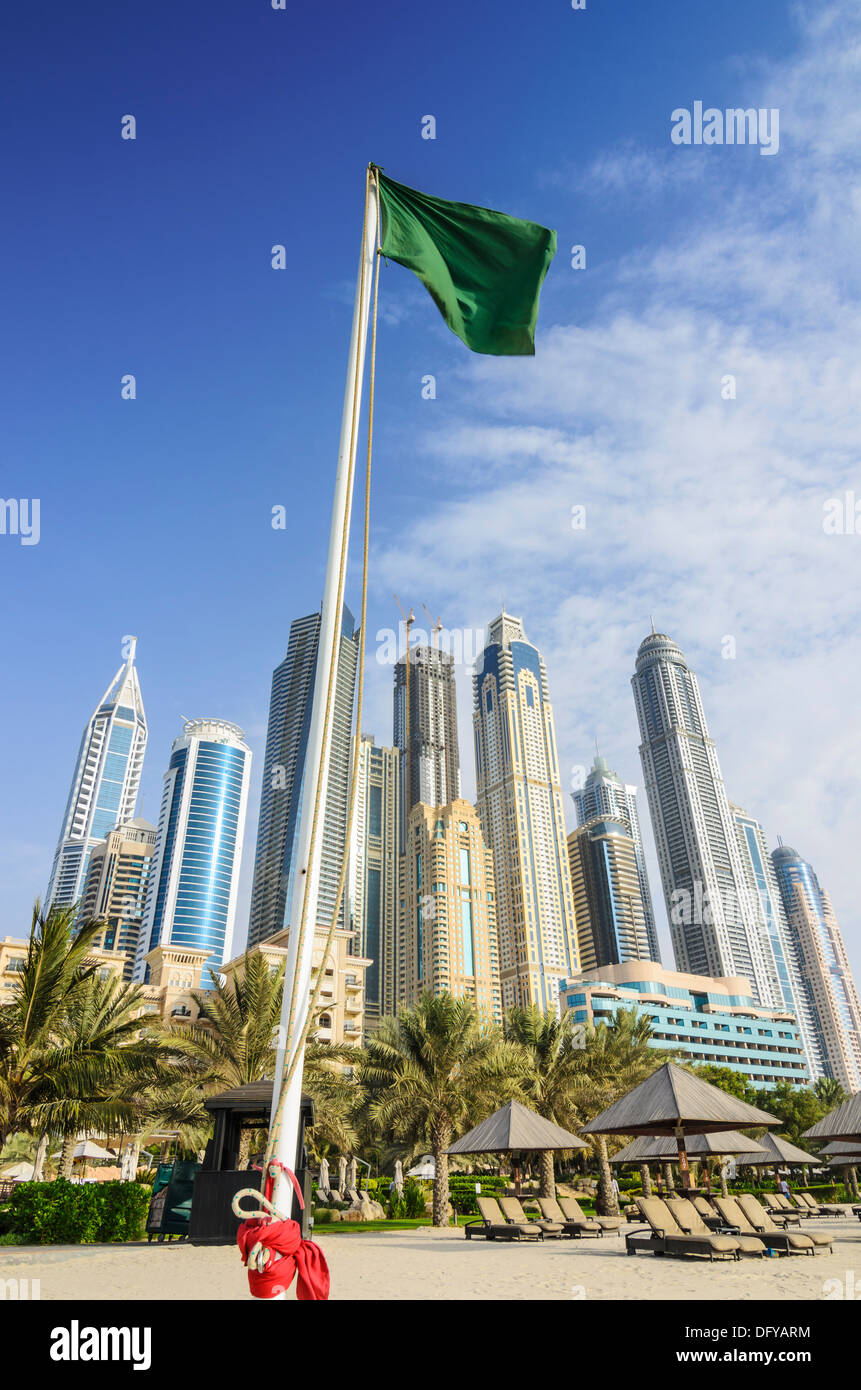Gratte-ciel de Dubaï Marina tower au-dessus d'un drapeau vert sur la plage de l'hôtel Westin Dubai Mina Seyahi Beach Resort Hotel, Dubai Banque D'Images