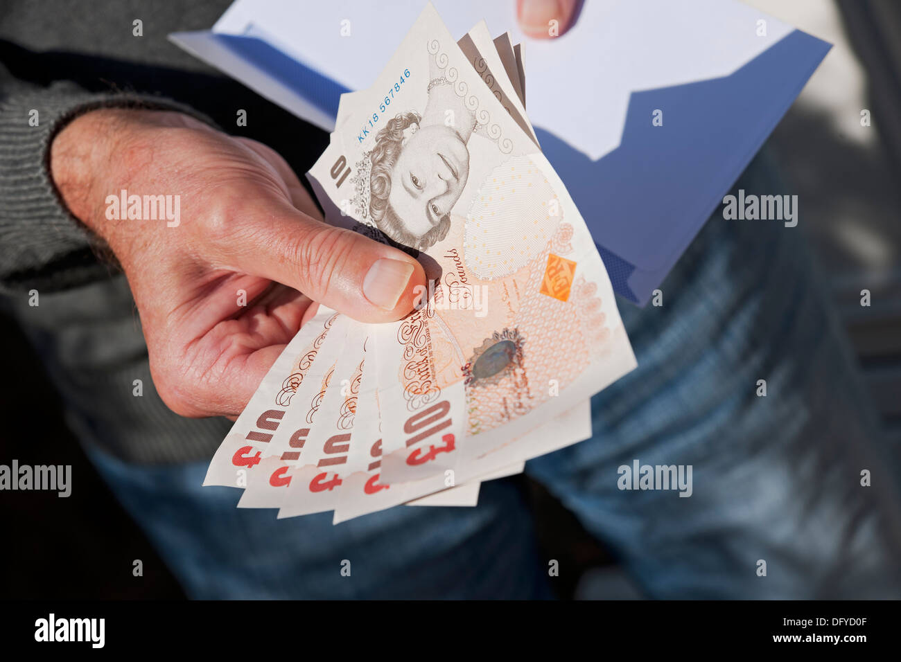 Gros plan de l'homme personne tenant la prise d'argent anglais dix livres billets de banque billet de banque £ 10 billets de banque corruption enveloppe blanche Angleterre Royaume-Uni Grande-Bretagne Banque D'Images