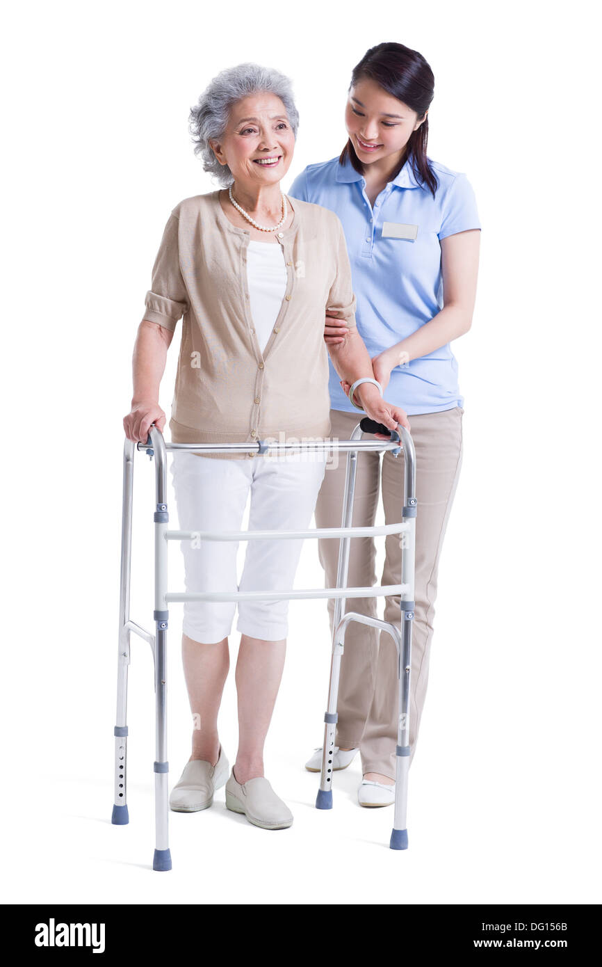 Infirmière auxiliaire féminine aidant les femme avec déambulateur Banque D'Images