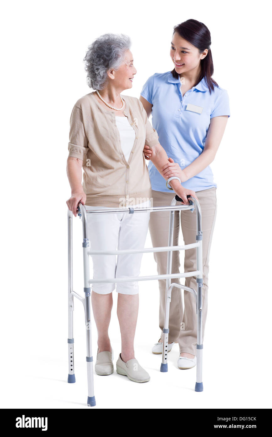 Infirmière auxiliaire féminine aidant les femme avec déambulateur Banque D'Images