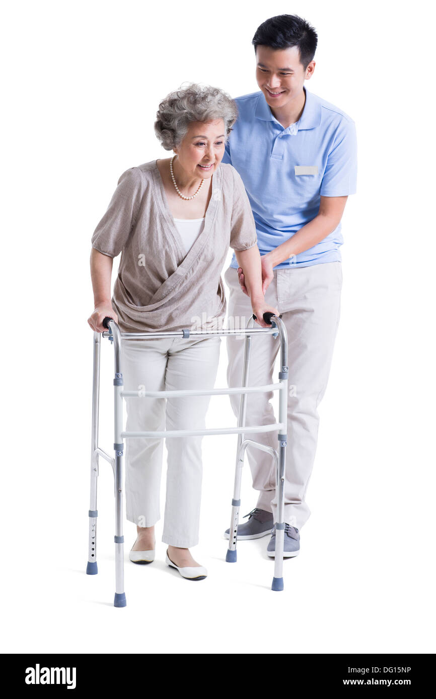 Assistant de soins infirmiers masculins aidant les femme avec déambulateur Banque D'Images