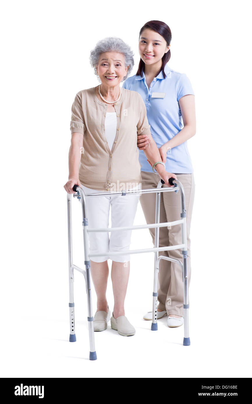 Infirmière auxiliaire féminine aidant les femme avec déambulateur Banque D'Images