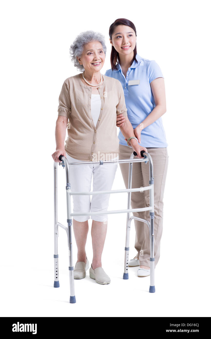 Infirmière auxiliaire féminine aidant les femme avec déambulateur Banque D'Images