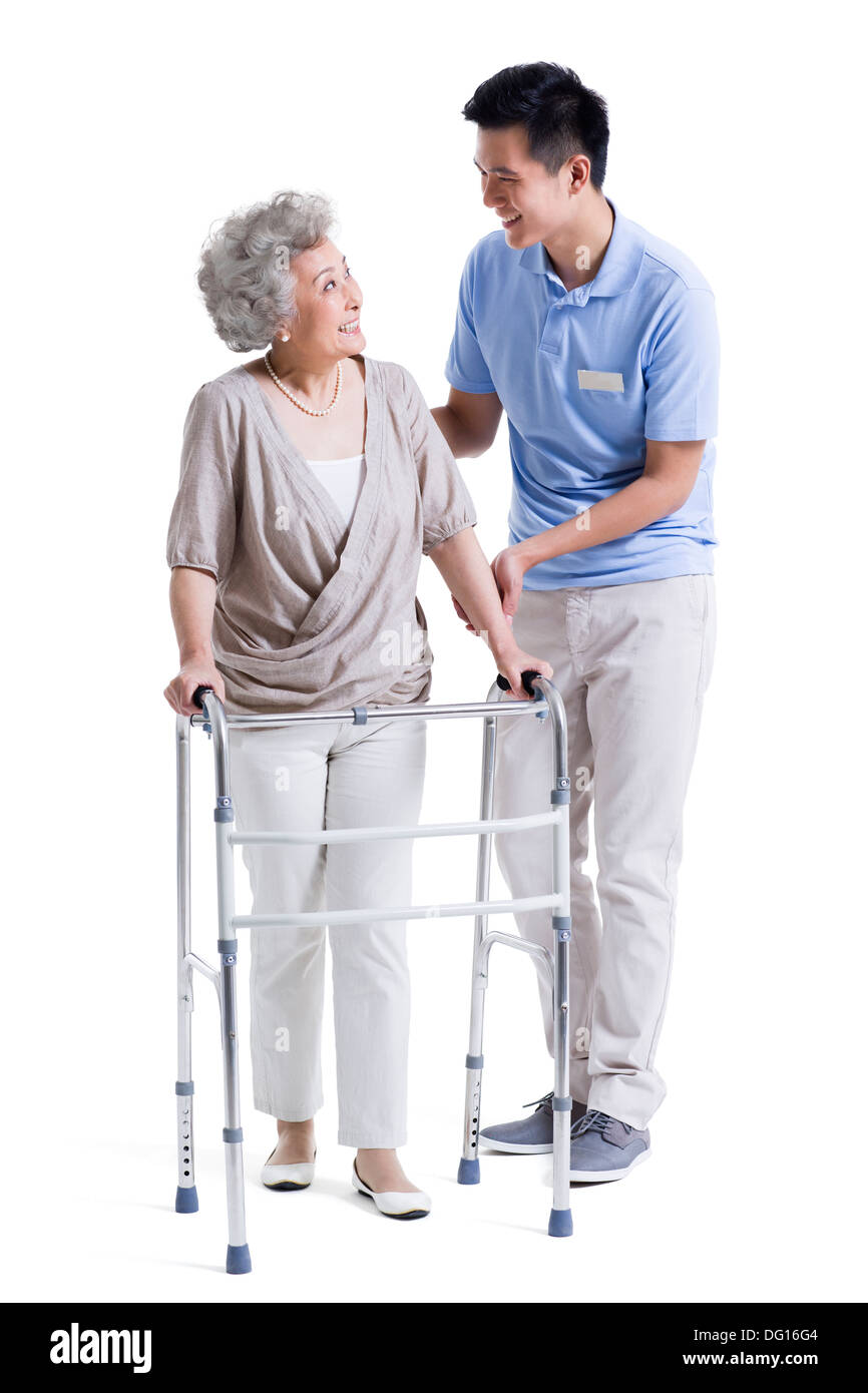 Assistant de soins infirmiers masculins aidant les femme avec déambulateur Banque D'Images