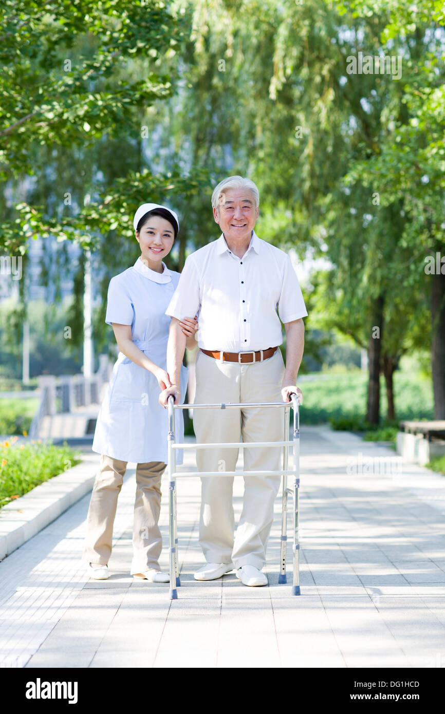 Man Walking avec déambulateur sous l'assistance de l'infirmière Banque D'Images