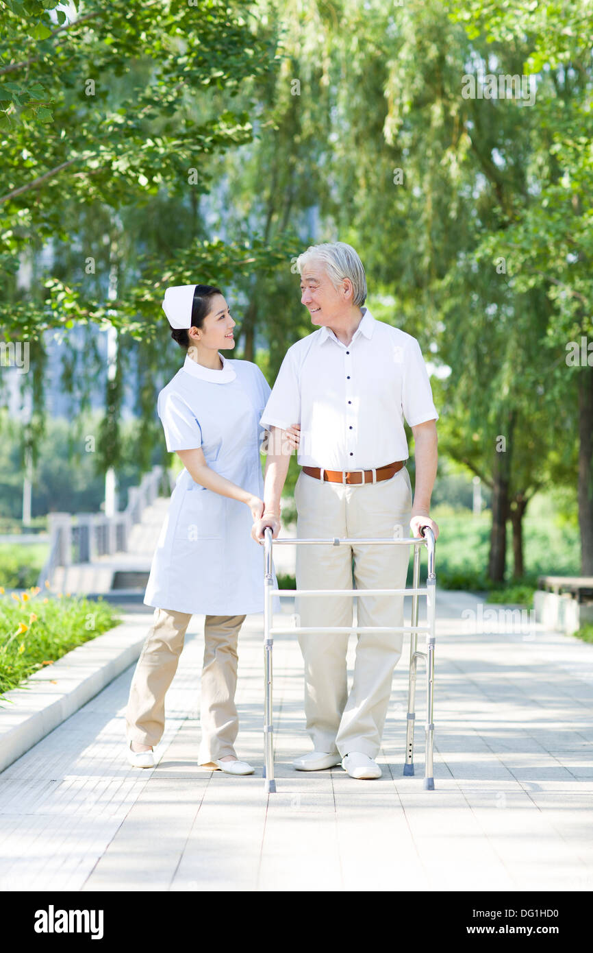 Man Walking avec déambulateur sous l'assistance de l'infirmière Banque D'Images