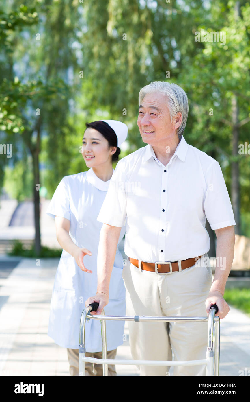 Man Walking avec déambulateur sous l'assistance de l'infirmière Banque D'Images