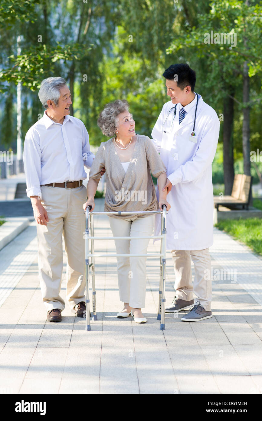 Senior woman walking with walking châssis sous l'assistance du mari et médecin Banque D'Images