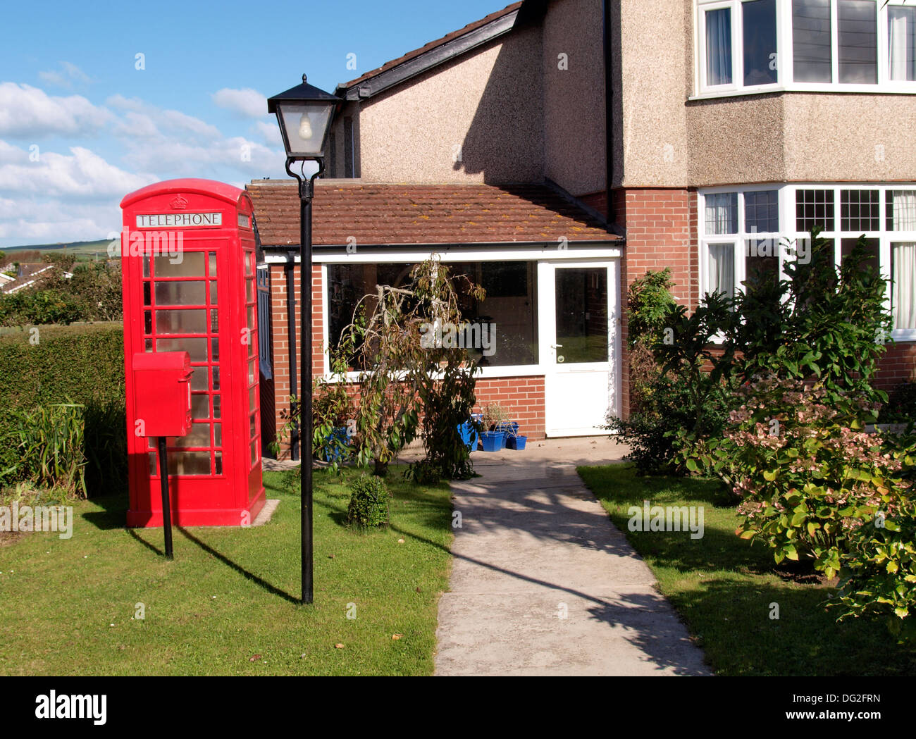 Jardin avec une boîte aux lettres rouge, téléphone rouge fort et d'un lampadaire, Bude, Cornwall, UK Banque D'Images