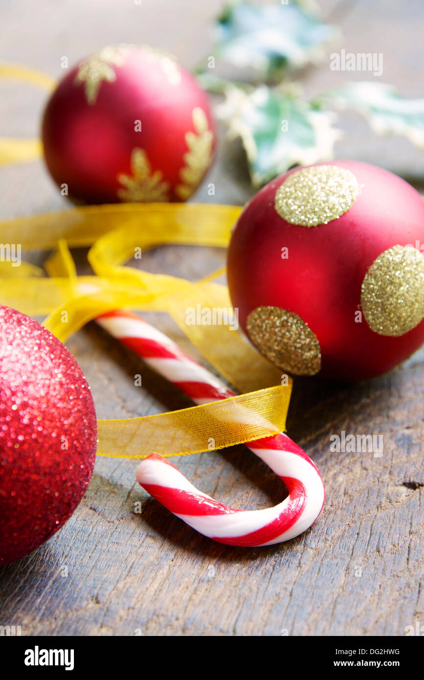 Un Peppermint Candy canes avec des boules de Noël et des feuilles de houx. Banque D'Images