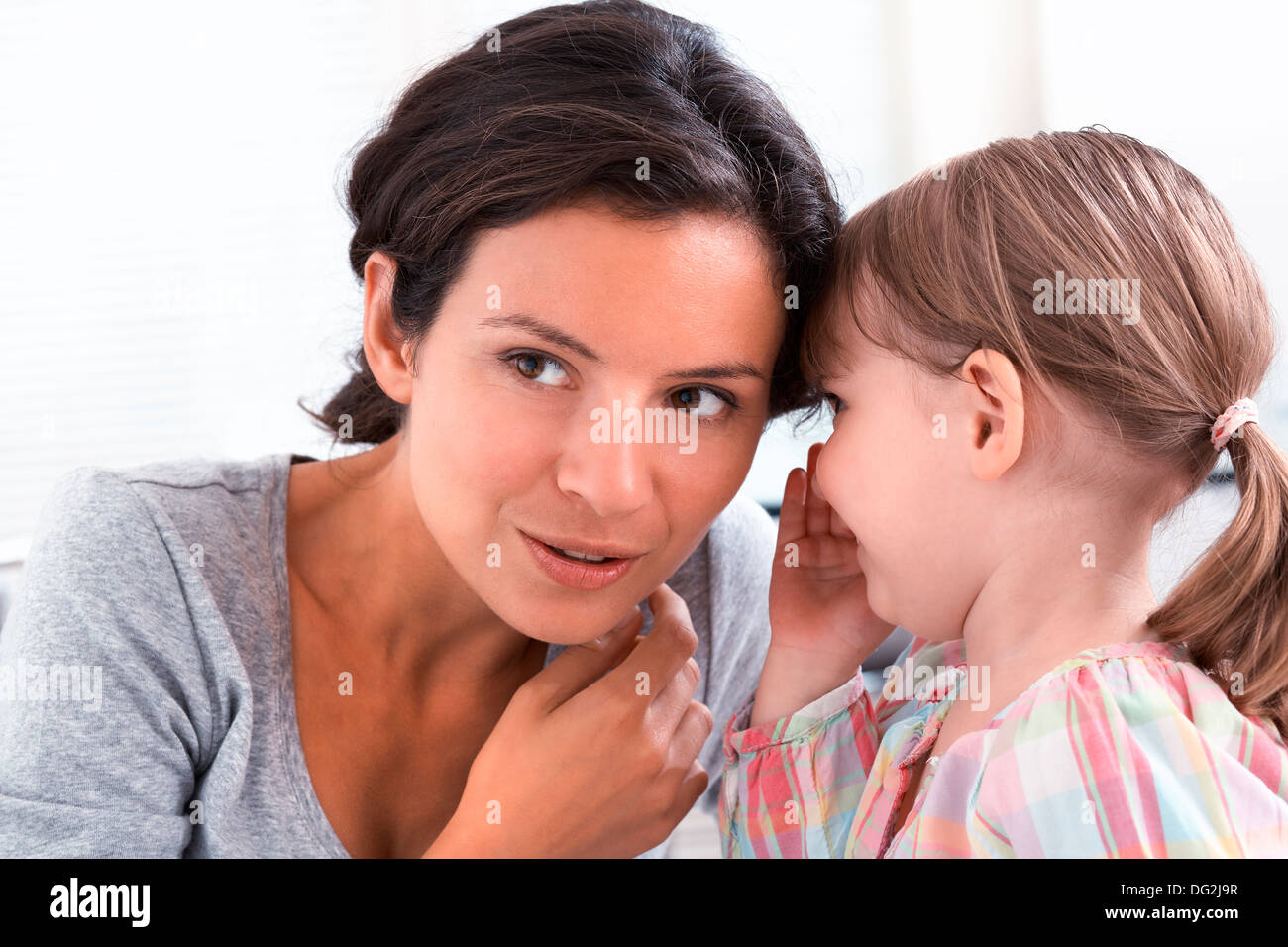 Mère heureuse avec sa fille dire un secret dans les portes Banque D'Images