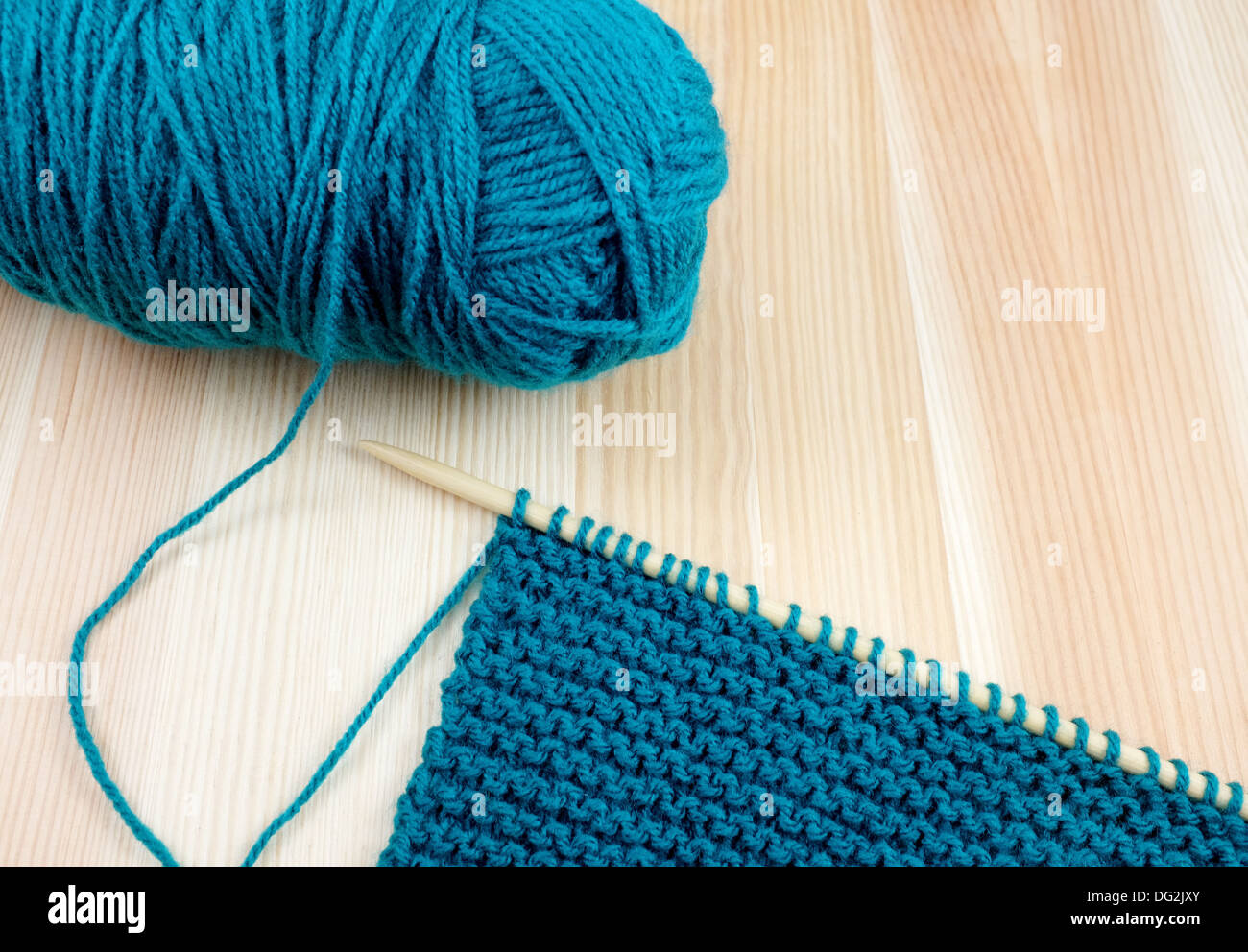 Libre de balle de laine bleu sarcelle avec longueur de garter stitch sur une aiguille à tricoter, sur bois Banque D'Images