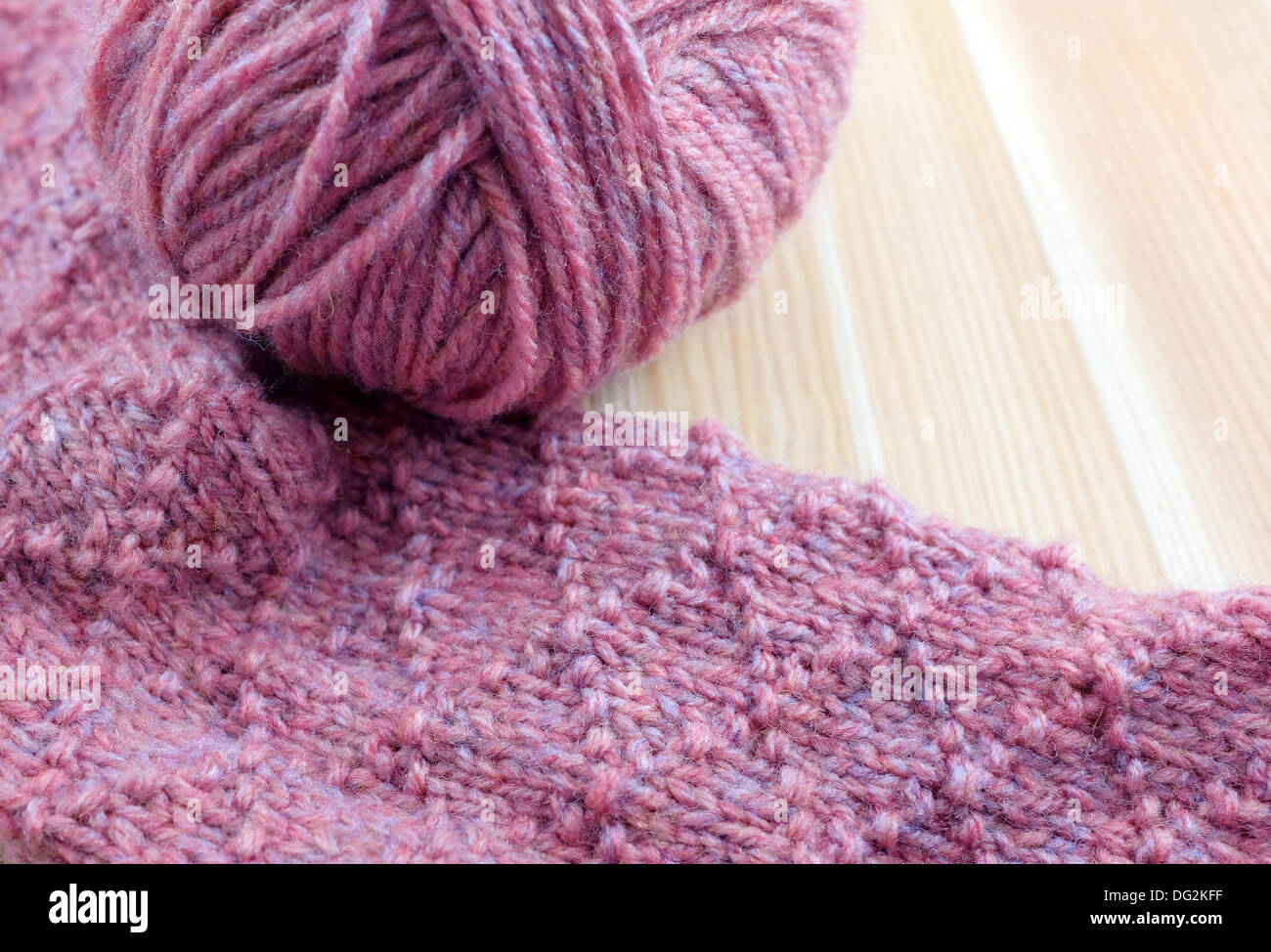 Tricot à motifs en fil rose avec balle de laine, on wooden table Banque D'Images