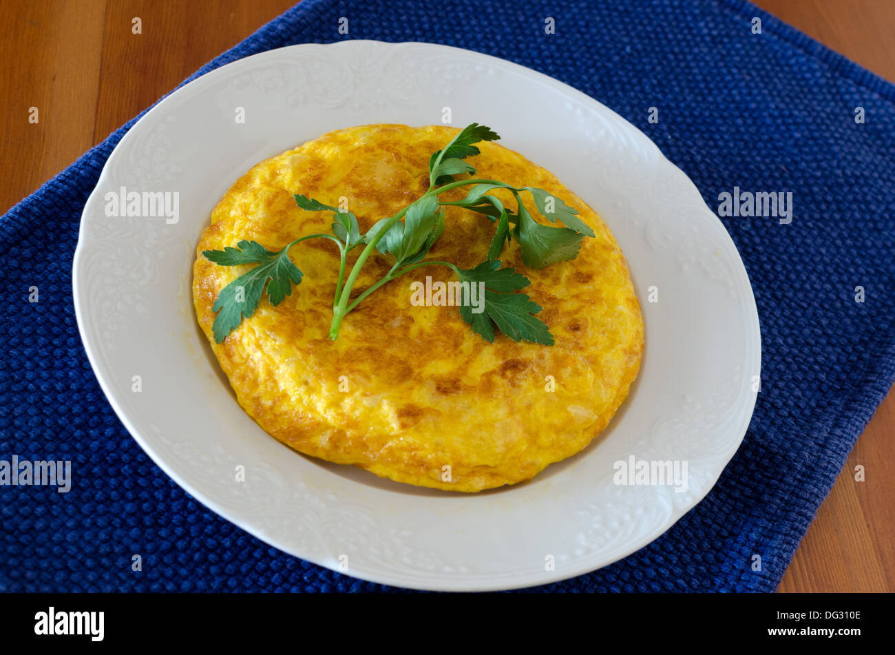 Cuisine typique espagnole ; une omelette faite avec des pommes de terre sautées et (parfois), l'oignon . Elle est ornée de feuilles de persil Banque D'Images